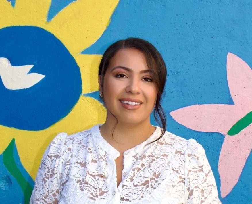 Portrait of Mirella in front of a colorful mural