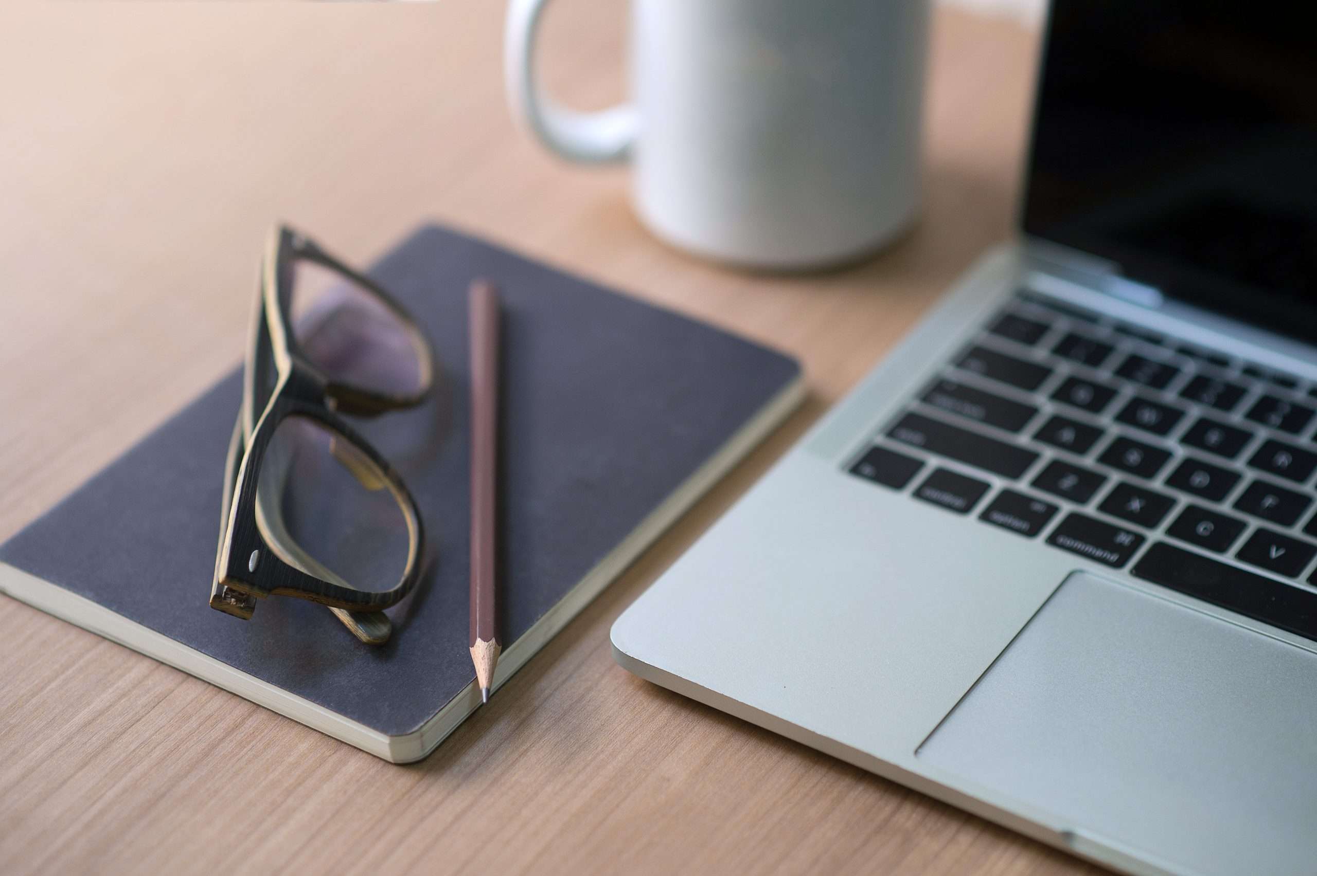 Writer’s career on the desk with white coffee mugs, notebooks, pencils, glasses and Macbooks