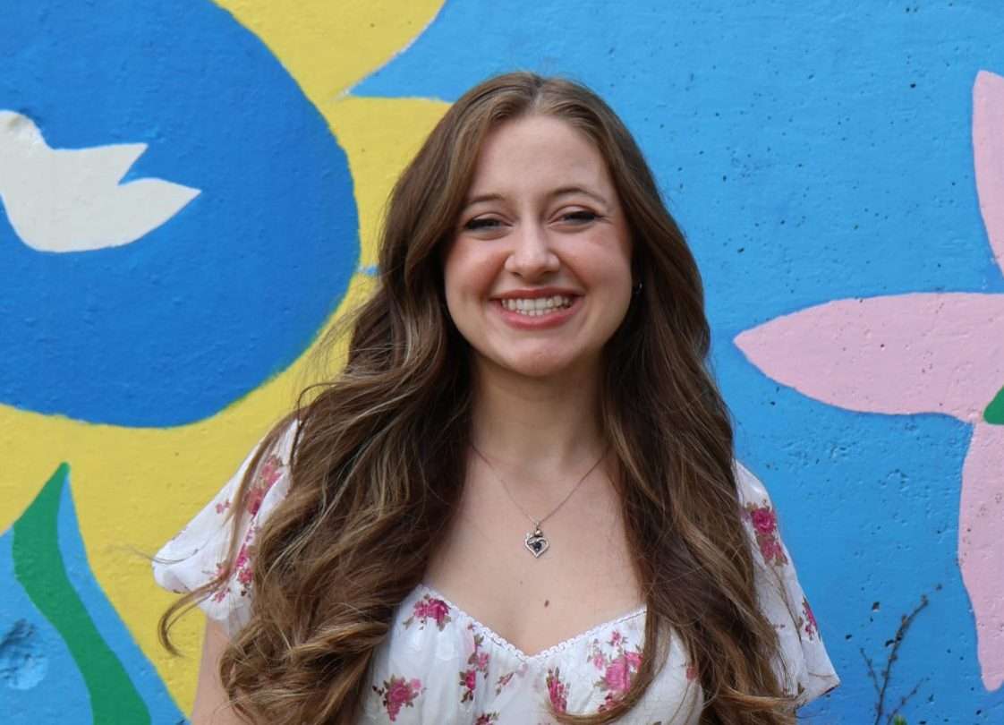 Portrait of Alyssa White in front of a colorful mural