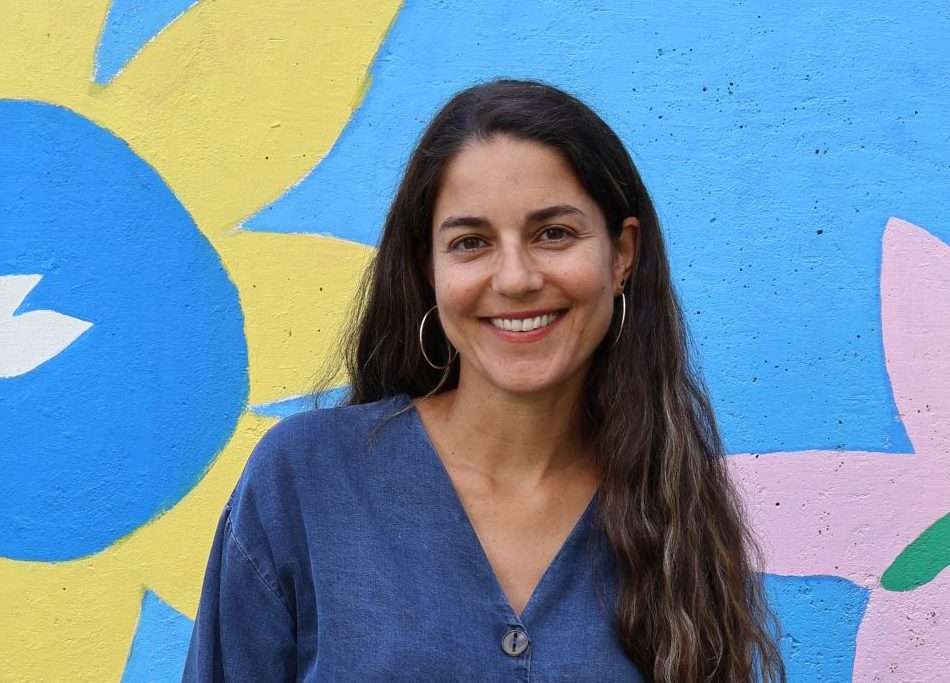 Portrait of Hannah Danino in front of a colorful mural