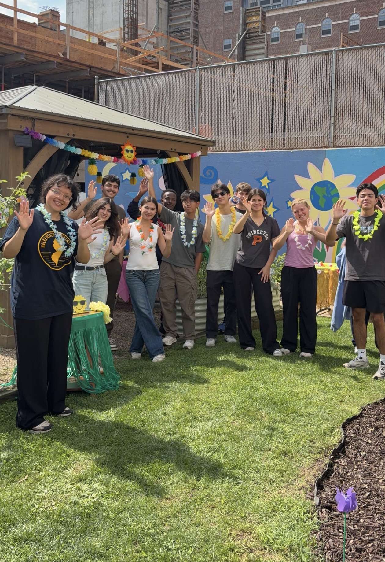Community members posing together in front of a colorful outdoor mural.
