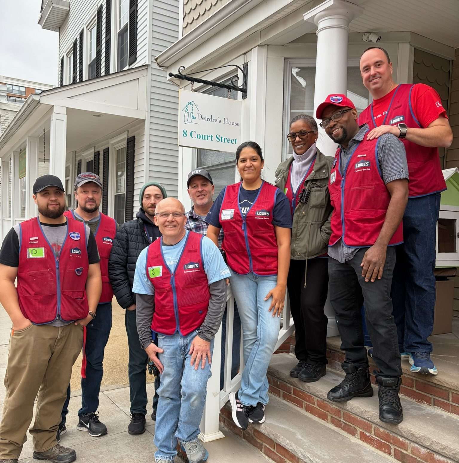 Group of volunteers wearing red vests standing outside a building.