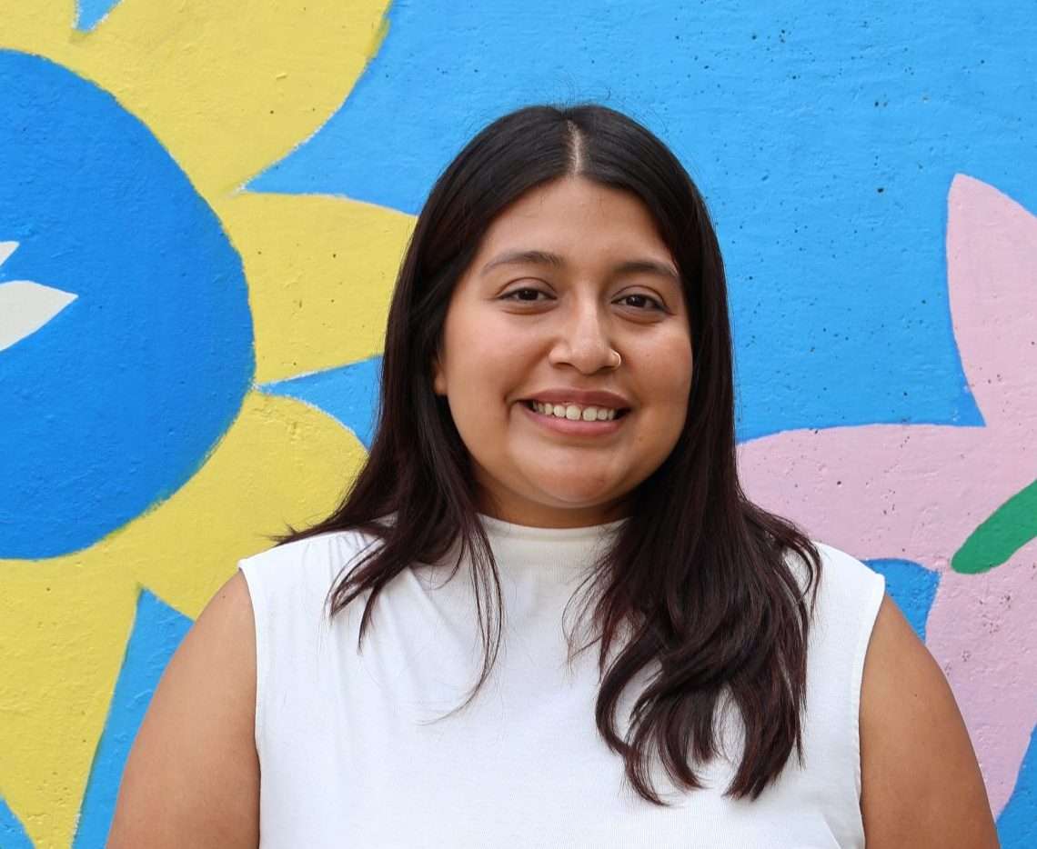 Portrait of Jissell Varela in front of a colorful mural