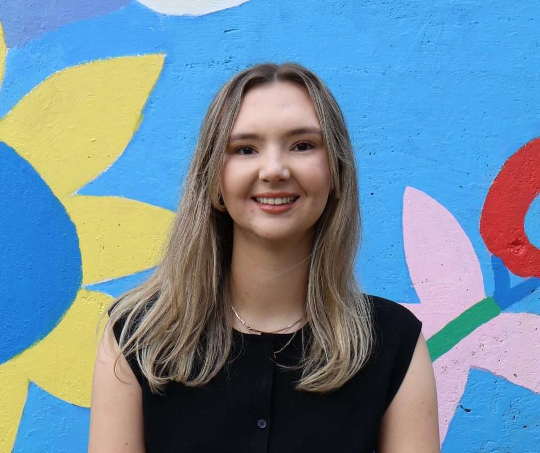 Portrait of Julia Gateman in front of a colorful mural