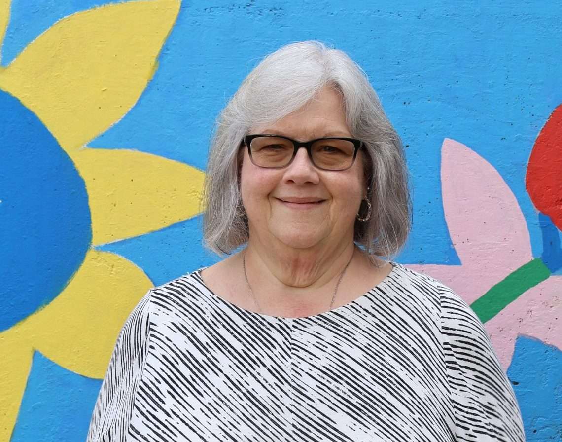 Portrait of Nancy Begin in front of a colorful mural