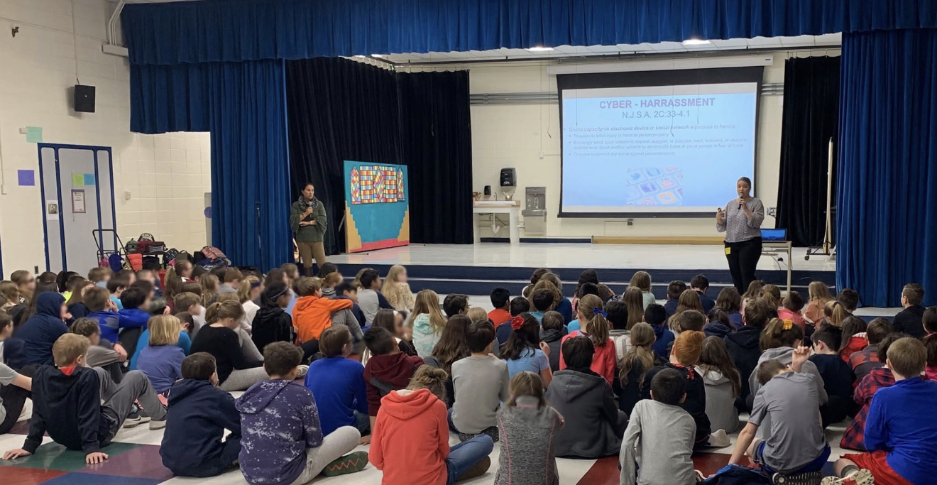 Presenter speaking to an audience of children during an educational assembly.