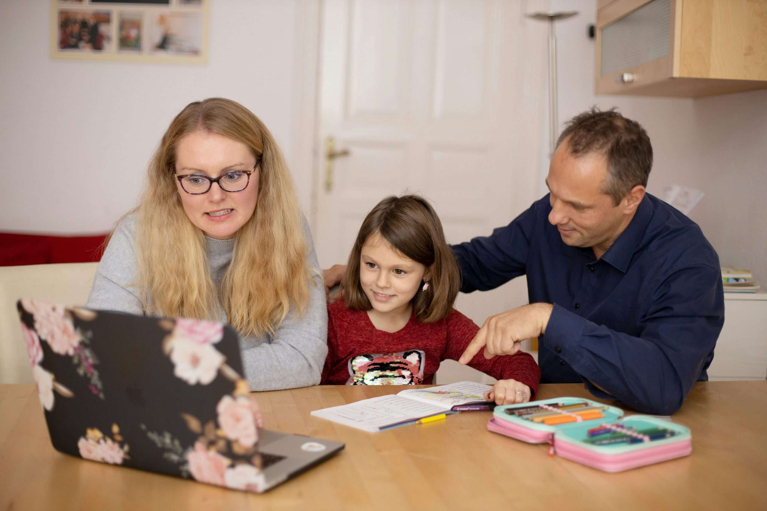 Adult helping children study together at a table.