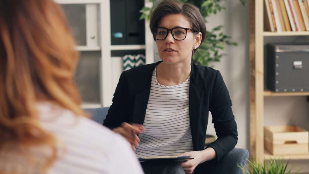 Woman with glasses speaking during a counseling session.